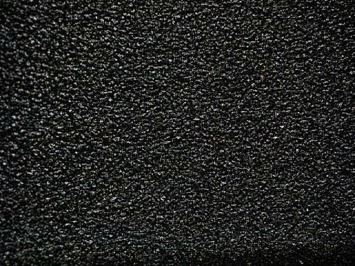 Microscope view of a genuine molded IC surface with sharp glass-filled texture, used as the reference baseline