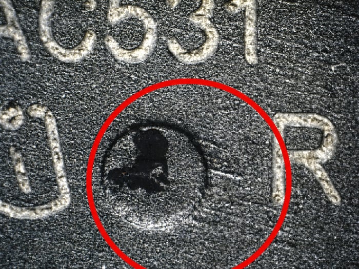 Microscope view of directional sanding marks on a counterfeit BTS443P surface, circled in red