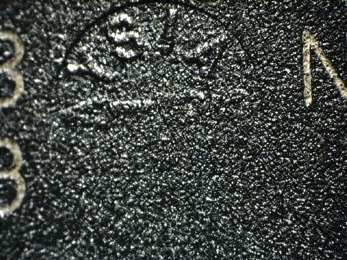 Counterfeit MAX500BCWE indent half filled with blacktopping, showing textured lettering