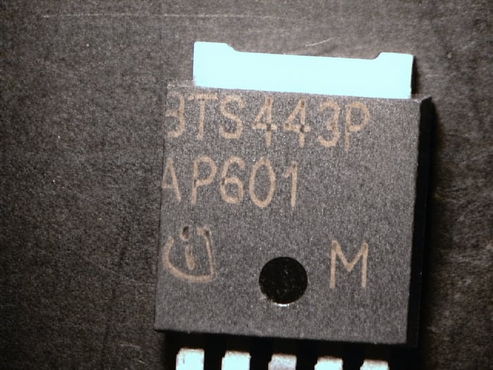 Counterfeit BTS443P AP601 with marking hanging off the edge, misaligned versus the rest of the reel